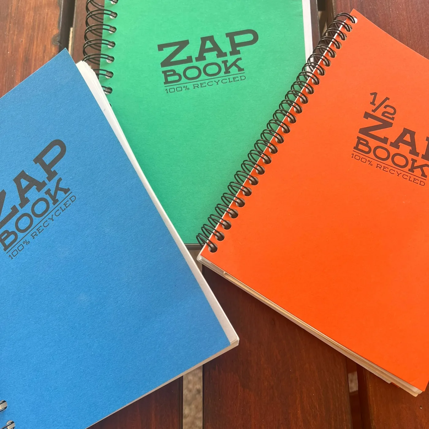 Trois cahiers ZAP BOOK bleu, vert et orange à larges spirales, photographiés par Pierre-François